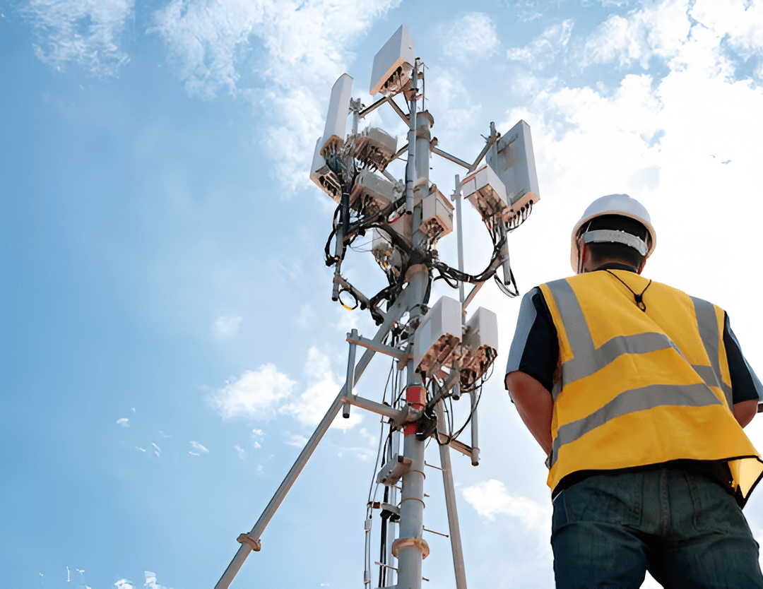 Telecommunications technician working beside a tower
